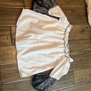 White shirt with black ruffles along the neck line and black covering near wrist